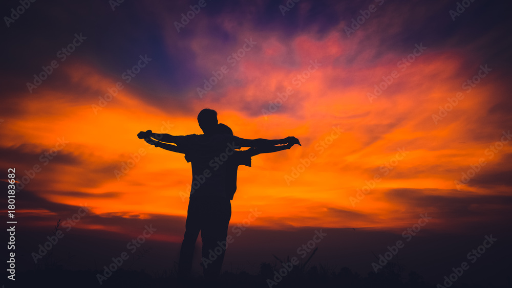 silhouette of a couple standing and stretch the arms look like the titanic at beauty sunset.