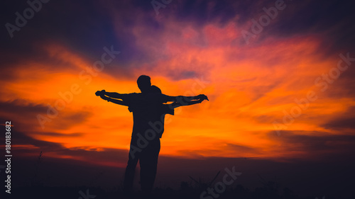 silhouette of a couple standing and stretch the arms look like the titanic at beauty sunset.