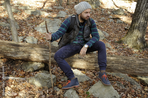 Man is sitting in autumn forest in the mountains. Hiking and traveling