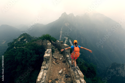 Photography successful woman hiker open arms to the great wall on the top of mountain