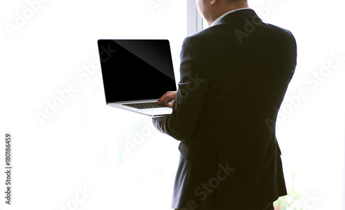 Rear view of a young businessman working of a laptop , blank screen for pupose design use .