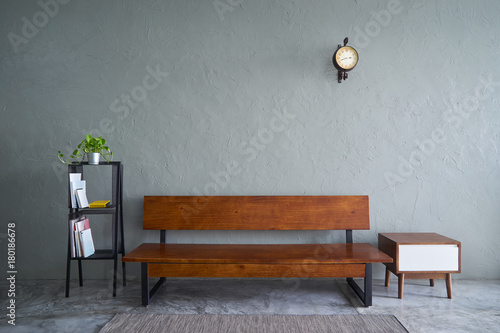 Modern living room with wooden bench sofa ,green plant , wooden tea table and clock. cement floor and concrete wall , Interior design with Loft style .