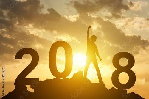 Man hand up on the peak of mountain and sunlight  with text 2018 sign happy new year calendar holiday concept