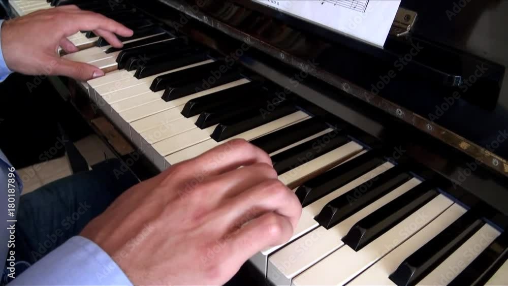 Hands of young man learning to play the piano, man wearing blue shirt playing classical piano with both hands while read the sheet music-Adrian Hands of young man learning to play the piano, man wearing blue shirt playing classical piano with both hands while read the sheet music-Adrian