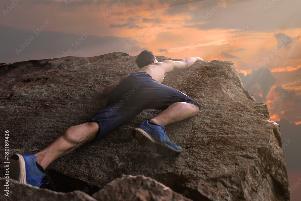 Asian man climbing rock mountain on sunset
