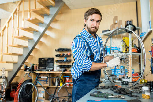 Specialist in repairing bikes tighten central cogwheel by workplace