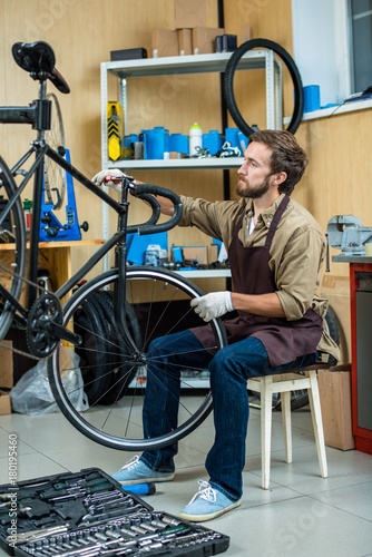 Owner of bike repair workshop fixing handlebars of bicycle