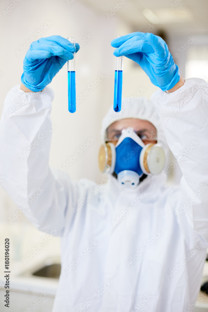 Gloved scientist holding two flasks with blue liquids Gloved scientist holding two flasks with blue liquids