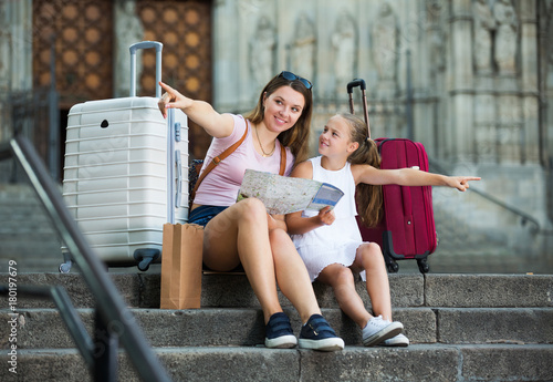 Fotografie mother and daughter travelers sitting on stone stairs