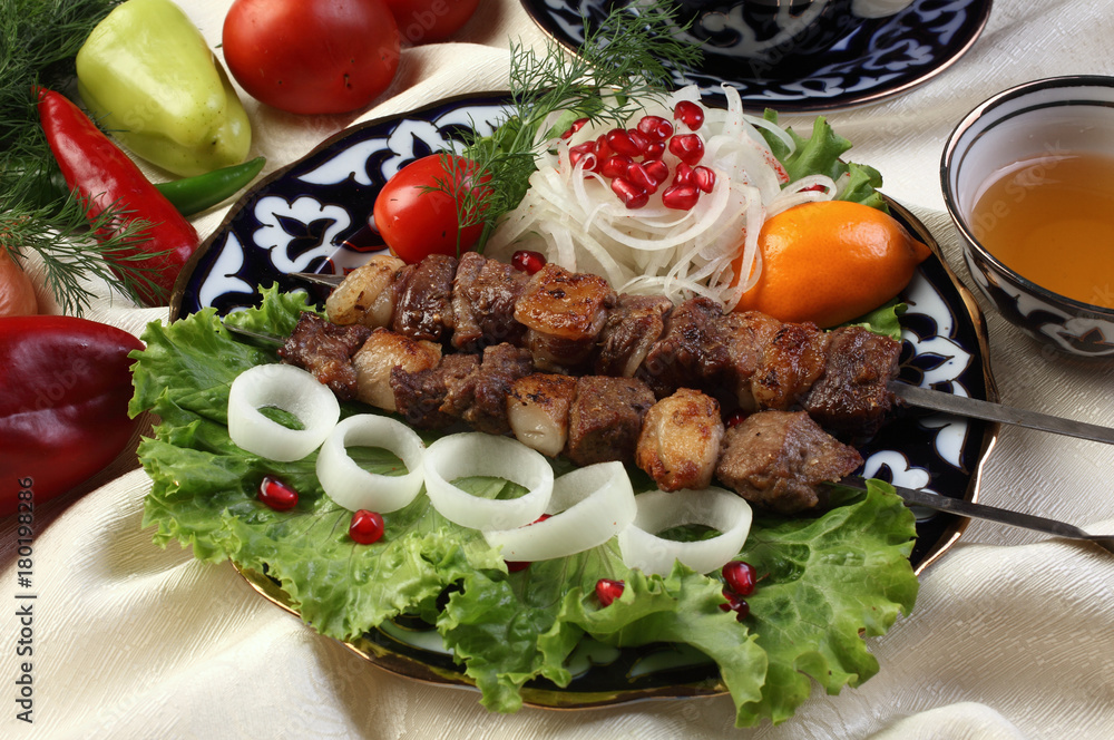 Uzbek Kebab.Sliced thigh or side of lamb marinated in wine vinegar,black pepper,coriander seeds,cumin.Served with onions and lettuce, garnish with pomegranate seeds.Uzbek cuisine.