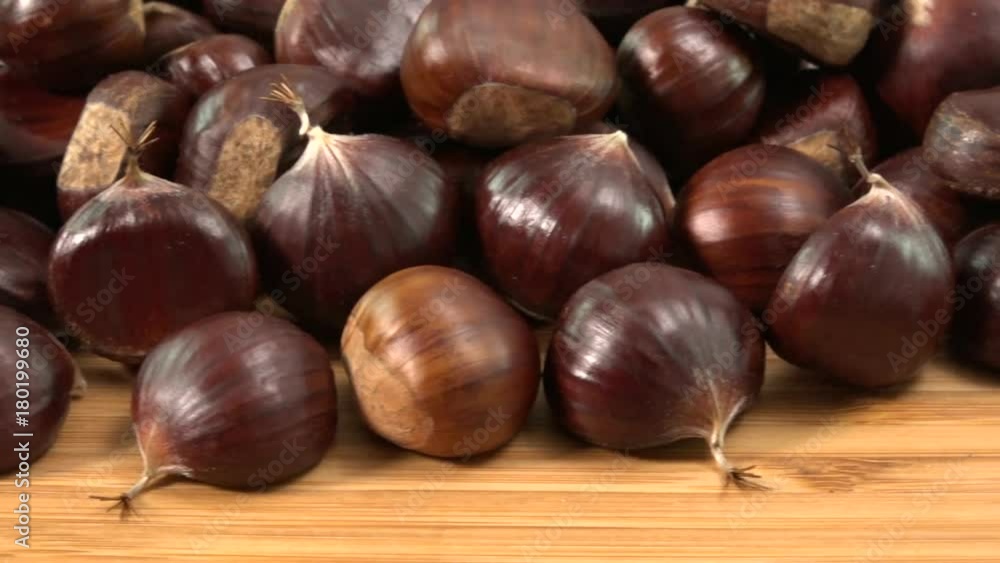 Sweet chestnut on wooden table, Castanea sativa fall food, organic snack. Typical autumnal fruit on wood background, close-up of forest harvest, dolly shot Sweet chestnut on wooden table, Castanea sativa fall food, organic snack. Typical autumnal fruit on wood background, close-up of forest harvest, dolly shot