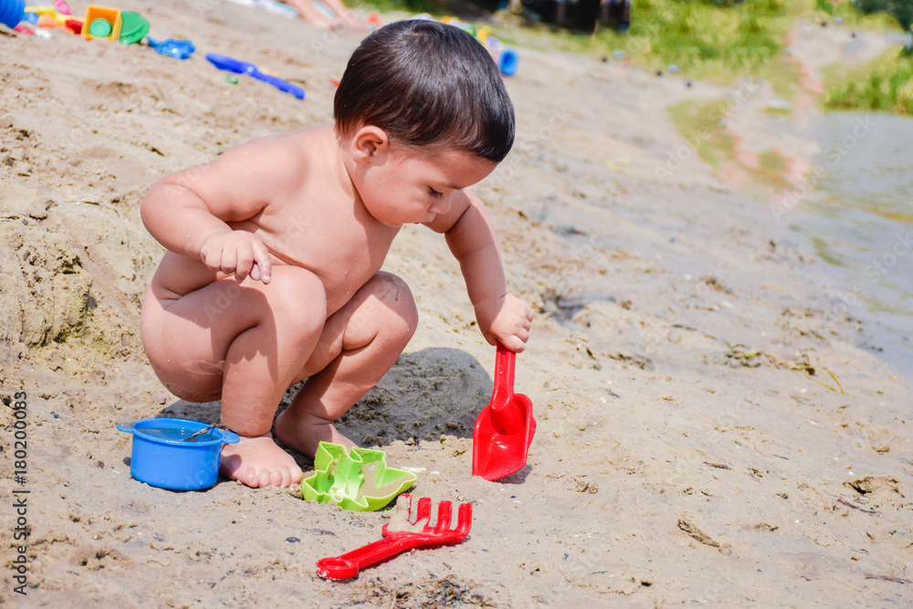 Little latin boy playing with sand on the beach. Little latin boy playing with sand on the beach.