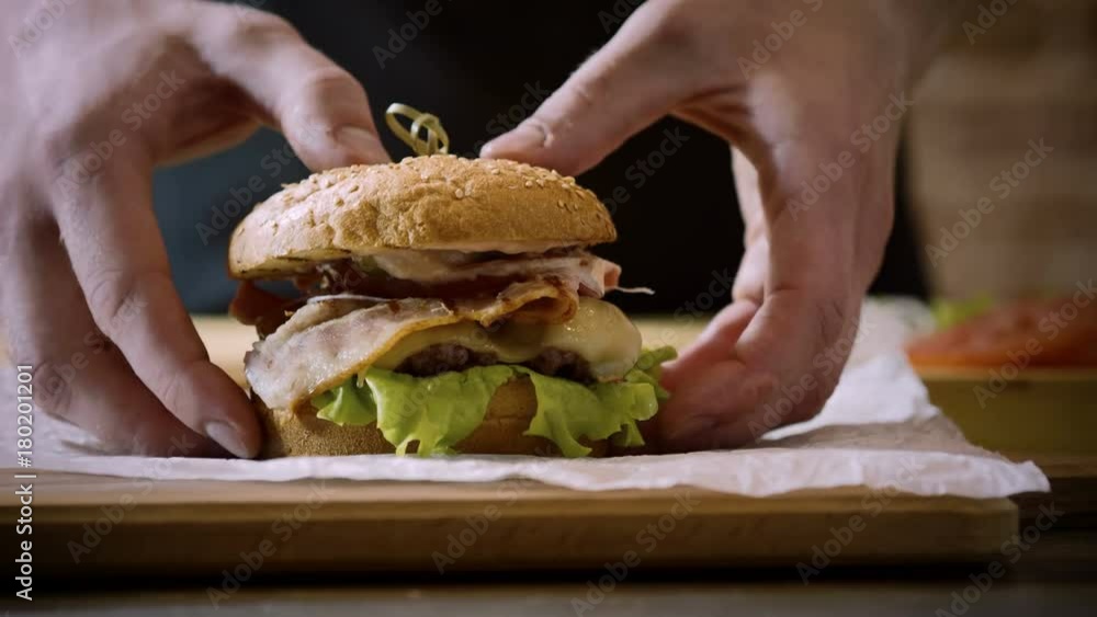 Cooking burger. Close-up shot of chef's hands putting a delicious prepared hamburger with beef rissole on a foreground. 4K Cooking burger. Close-up shot of chef's hands putting a delicious prepared hamburger with beef rissole on a foreground. 4K