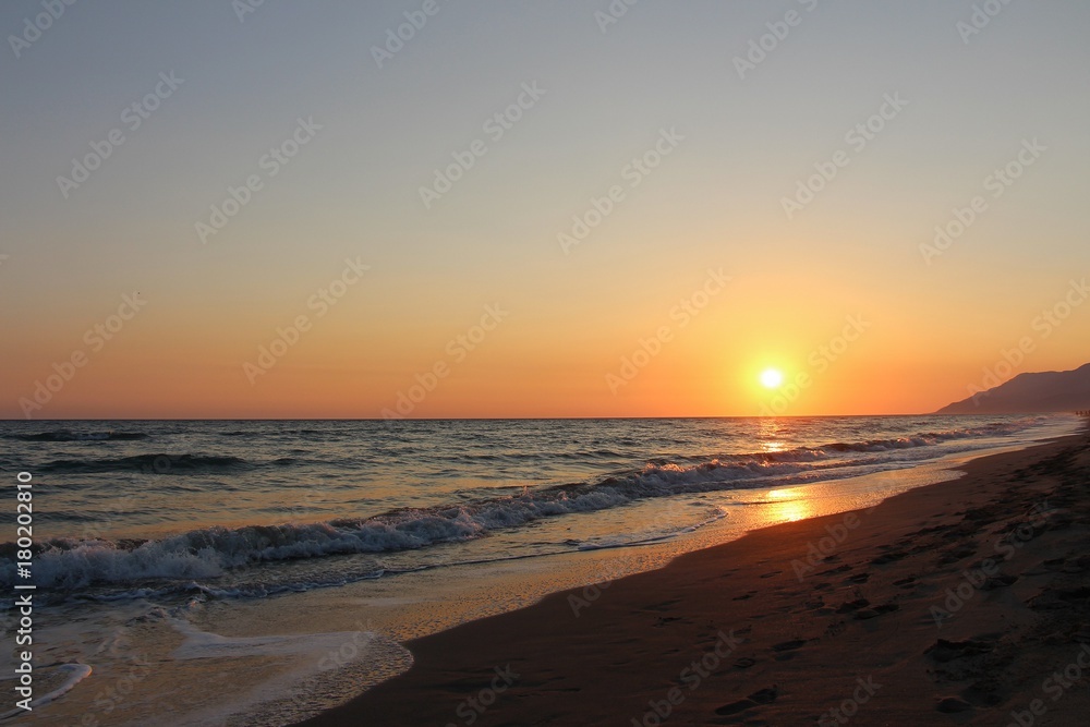 sunset in the sandy beach and wavy sea
