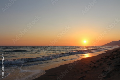 sunset in the sandy beach and wavy sea