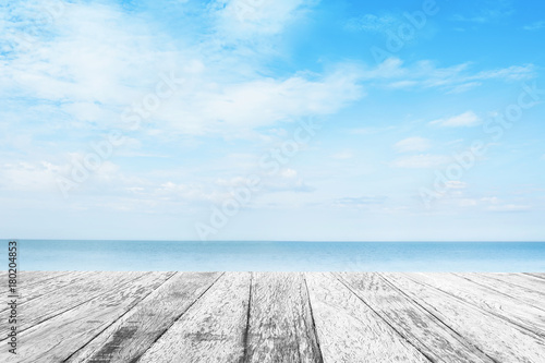 The blur cool sea background with wood floor foreground on horizon tropical sandy beach  relaxing outdoors vacation with heavenly mind view at a resort deck touching sunshine, sky surf summer clouds. © apichart