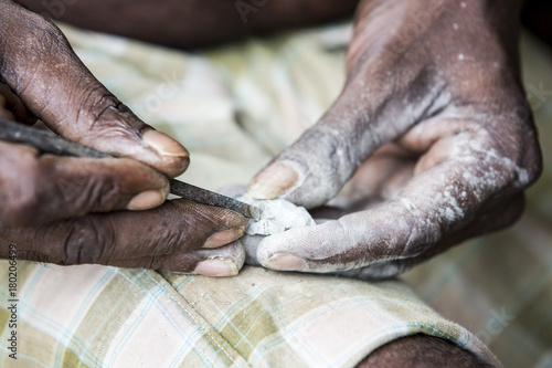 Close up of senior indian asian man sculptor carver hands working on his marble sculpture with chisel. photo