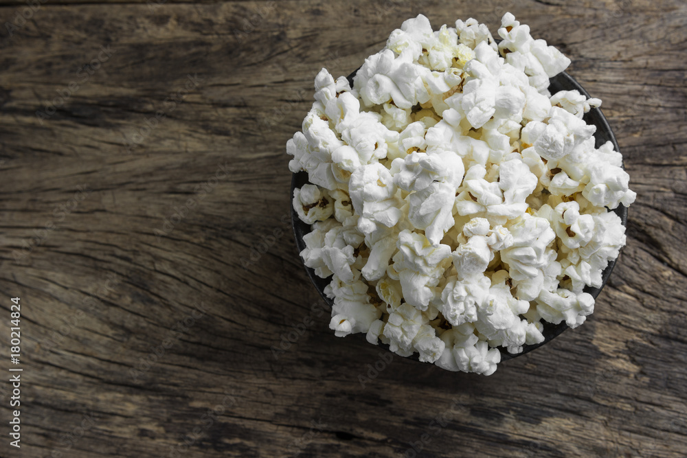top view of crispy popcorn in a ceramic bowl on old and crack wooden board, close up. top view of crispy popcorn in a ceramic bowl on old and crack wooden board, close up.