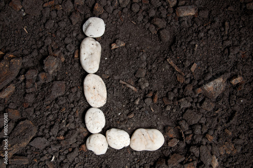 English alphabet (L - alphabet) from the white rock on the soil