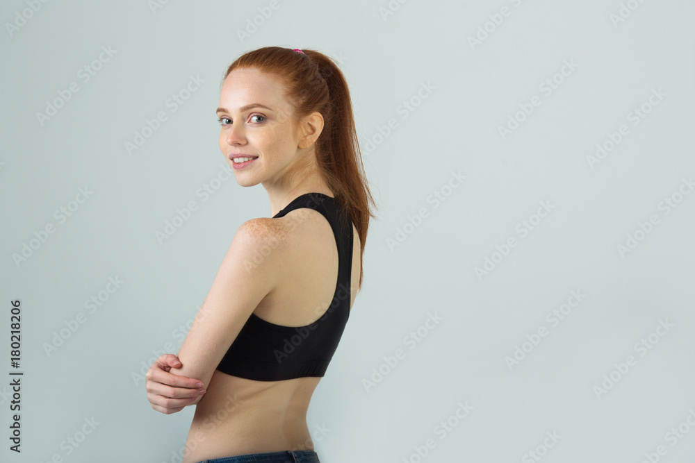 beautiful slender girl with a smile with red hair in sportswear on a light background beautiful slender girl with a smile with red hair in sportswear on a light background