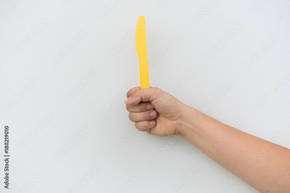 Yellow plastic knife in hand on white background Yellow plastic knife in hand on white background