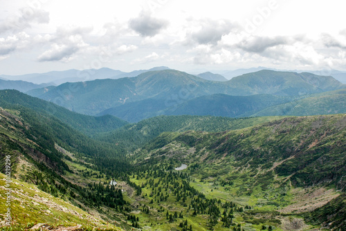 Mountain valley landscape on with green trees and lakes with mountain layers background