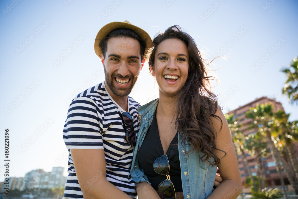 Happy man in hat standing with girlfriend outside laughing Happy man in hat standing with girlfriend outside laughing