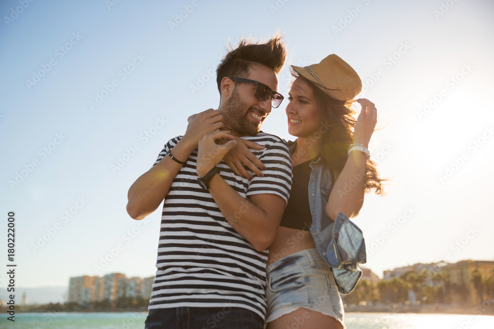 Happy woman in hat embracing her boyfriend looking at him Happy woman in hat embracing her boyfriend looking at him