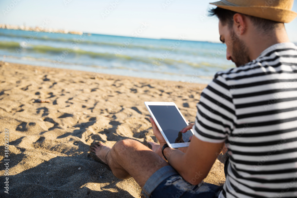 Man sitting on beach reading ebook