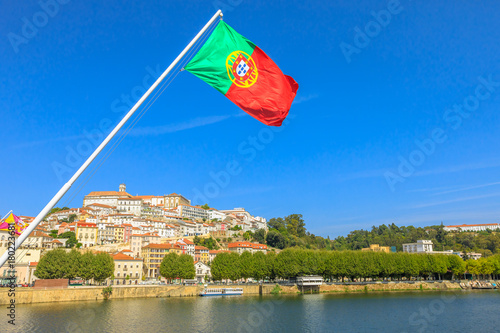 Panoramic view of old Coimbra city and Mondego river from Santa Clara bridge with flag of Portugal flying on foreground.Coimbra is famous for its University, founded in 1290, among the first in Europe photo