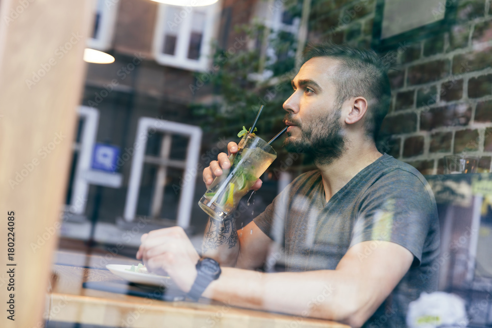 Obraz premium Man drinking cold fit bewerage in a cafe.