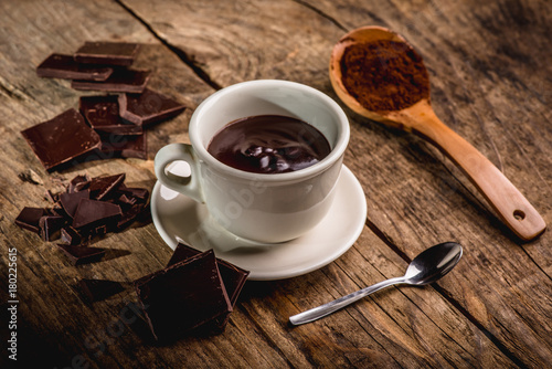 chocolate cup on wooden table with dark chocolate and powder