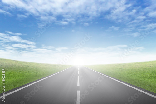 asphalt road through the green field and clouds on blue sky in summer day