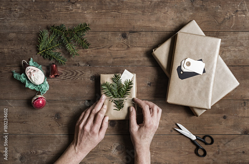 Woman wrapping Christmas presents on wooden table photo