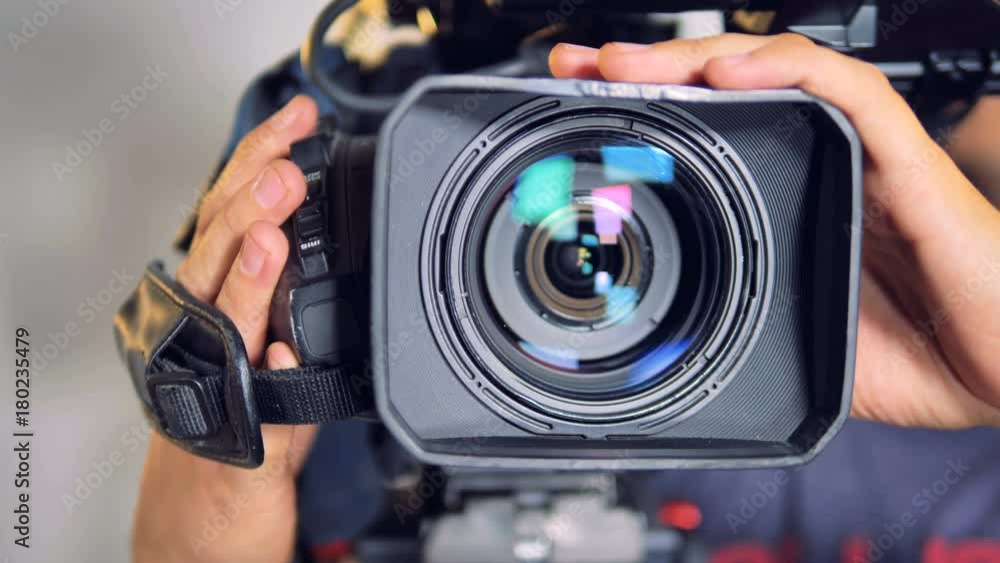 Close-up view on a video camera moved by male hands. 
