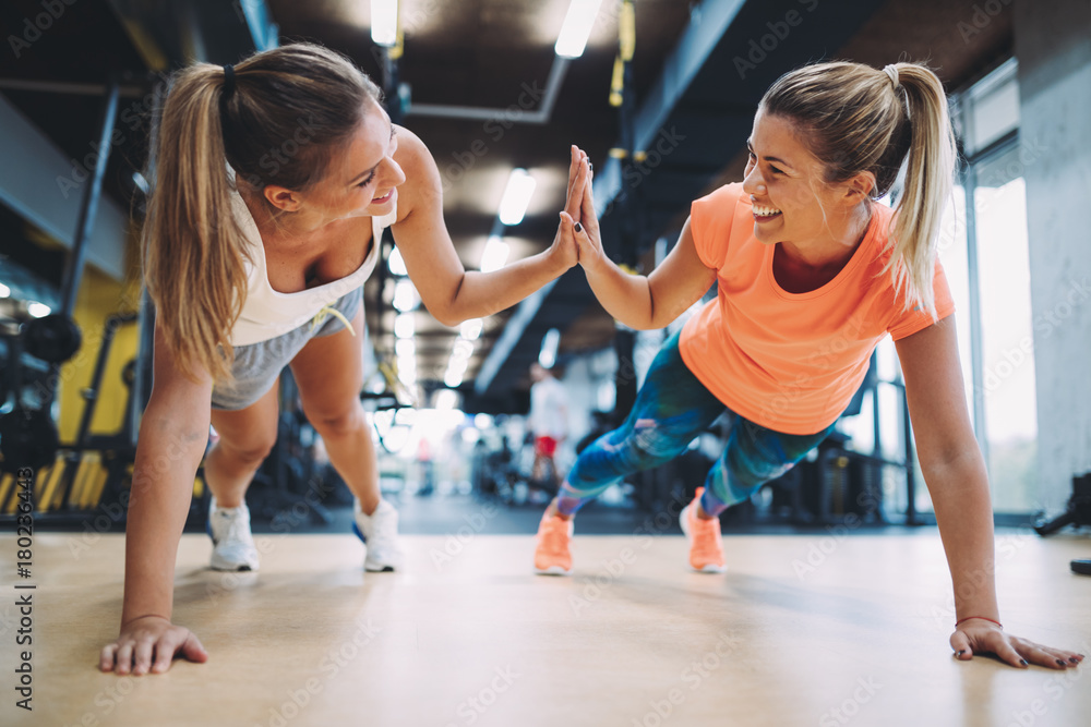 Two sporty girls doing push ups in gym - obrazy, fototapety, plakaty 