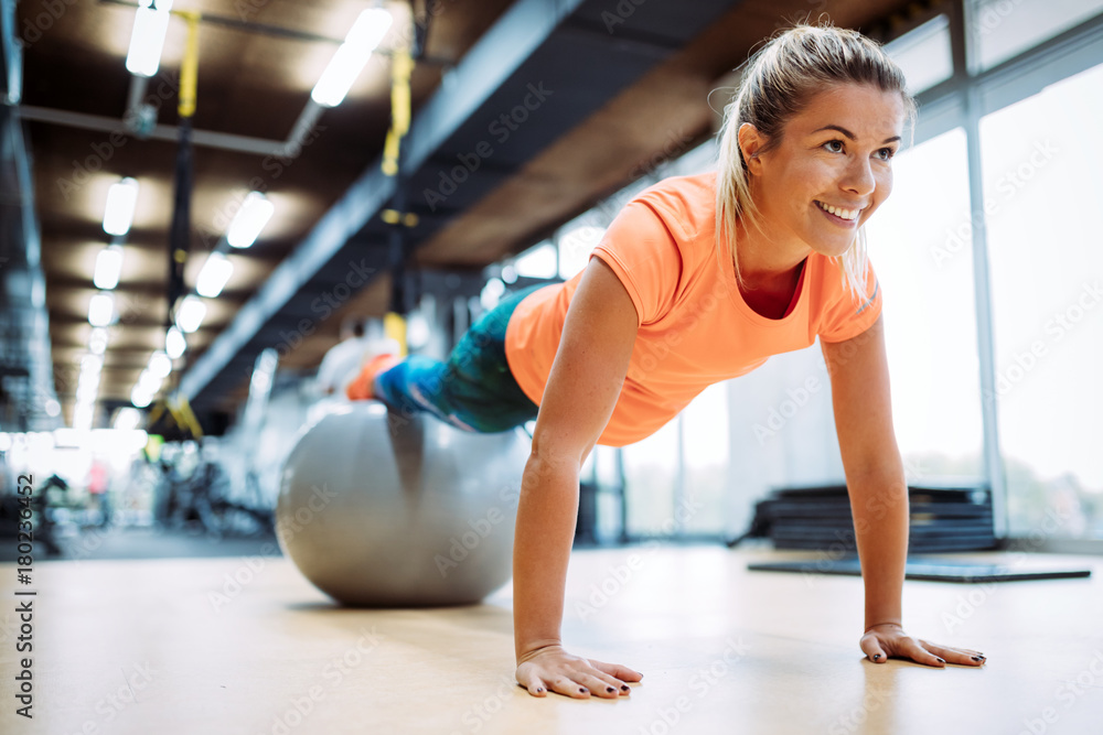 Young attractive woman doing push ups using ball - obrazy, fototapety, plakaty 