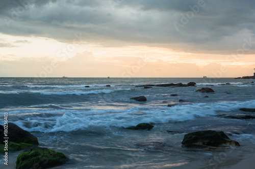 Sunset in Cambodia at the seaside. Sea waves roll on sands and rocks. © rhzr