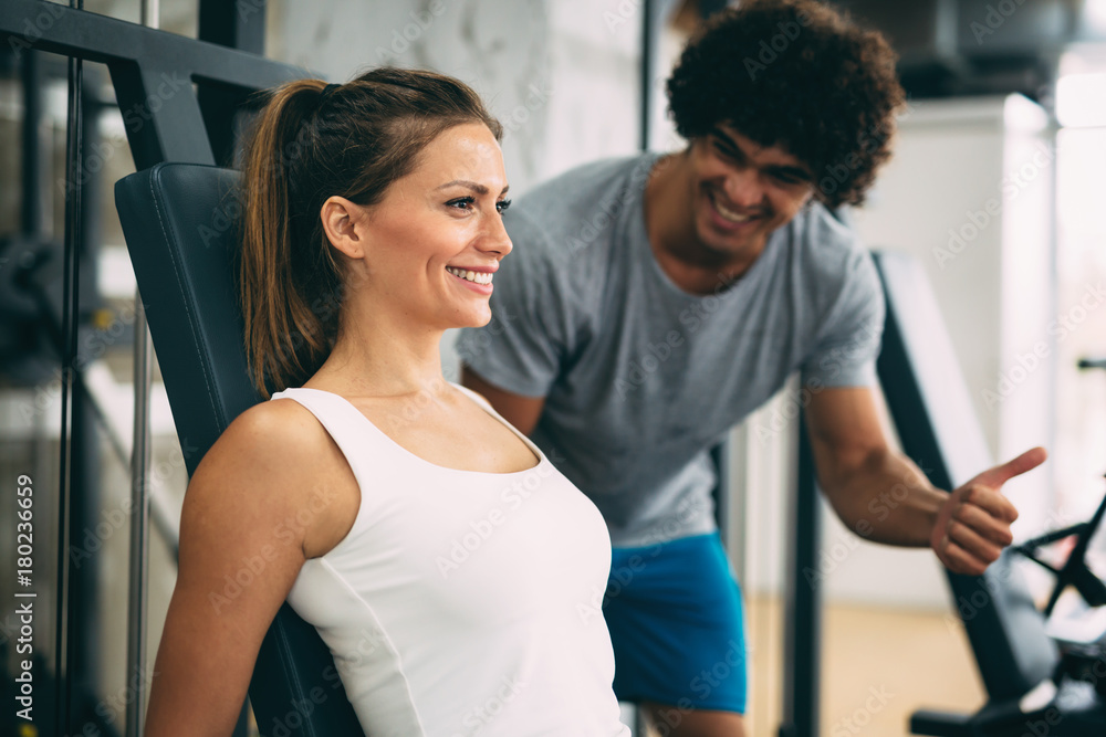 Obraz premium Young beautiful woman doing exercises with personal trainer