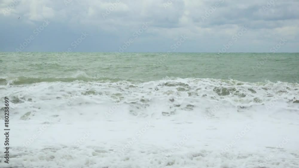 A foamy wave on the shore in a gray green sea under a dark blue sky A foamy wave on the shore in a gray green sea under a dark blue sky