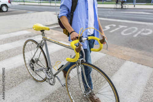 Young man pushing his bike on zebra crossing, partial view