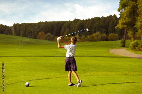 Boy golf player hitting by iron from fairway at golf course