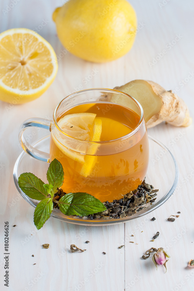 A glass cup of green natural tea with ginger, lemon, mint and honey on wooden rustic background. Healthy drink.