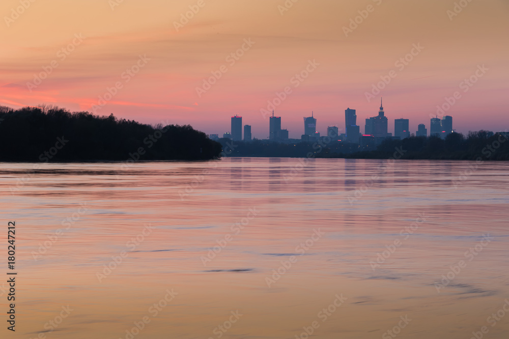 Red orange color twilight in Warsaw. City skyline with skyscrapers and the Vistula River