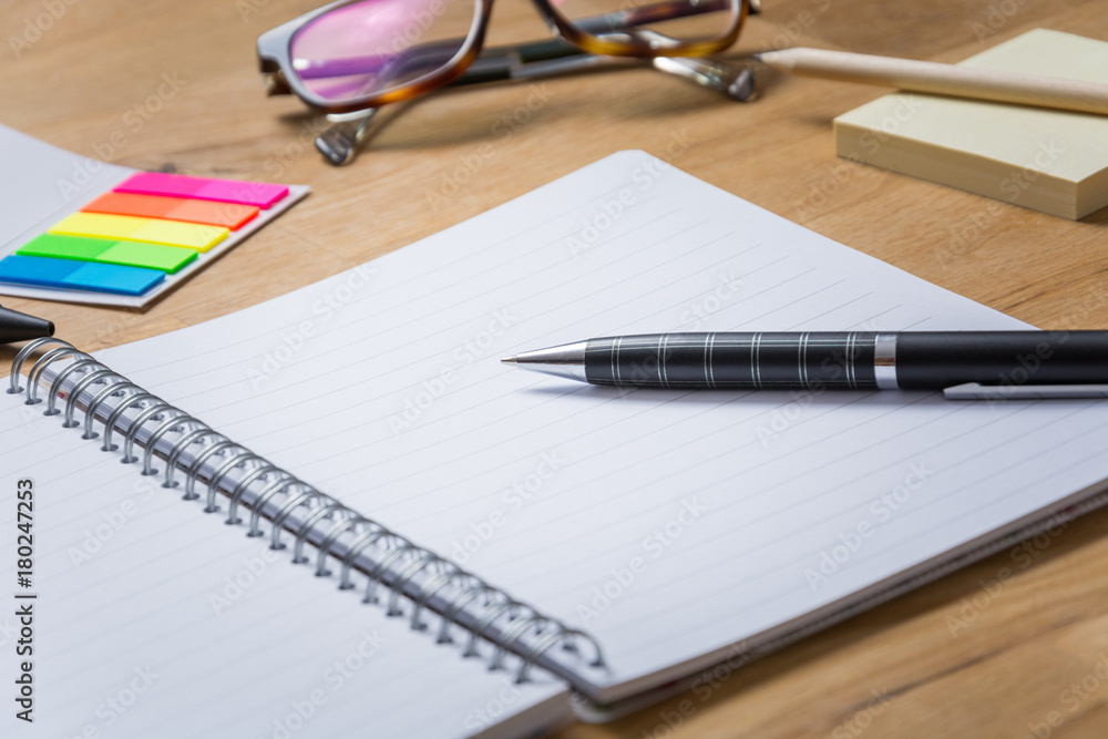 Empty open notepad with pen and other accessories on a wooden table from the side Empty open notepad with pen and other accessories on a wooden table from the side