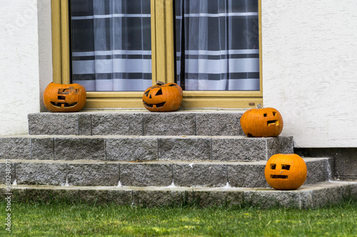 four orange heads drawn from the pumpkin on the stairs of the house