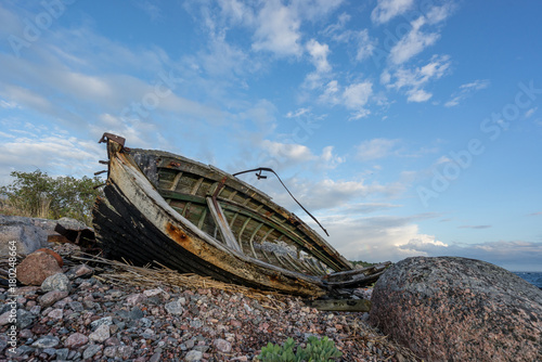 Old boat, shore, evening light, sunset, clouds and architecture concept in the Baltic Sea. Mohni, small island in Estonia, Europe. photo