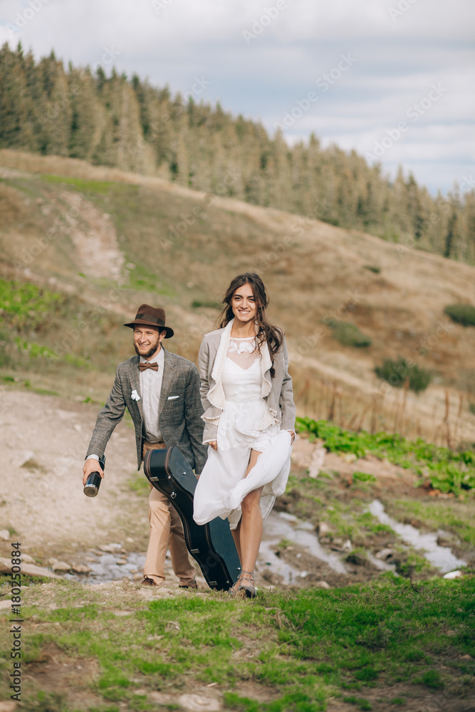 Bride and groom go for walk in Carpathians mountains.