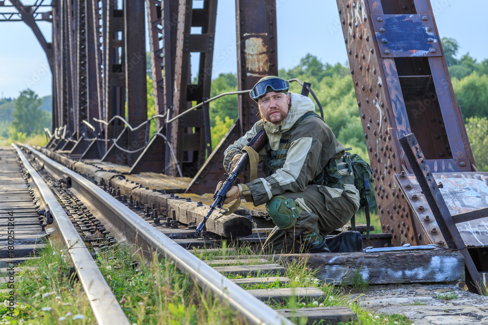 A serviceman on duty on a railway bridge with an automatic weapon A serviceman on duty on a railway bridge with an automatic weapon