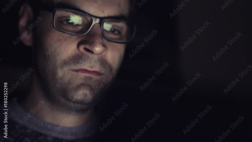 Gambling addicted man with glasses in front of online casino slot machine on laptop computer at night - loosing his money. Dramatic low light grain shot. Gambling addicted man with glasses in front of online casino slot machine on laptop computer at night - loosing his money. Dramatic low light grain shot.
